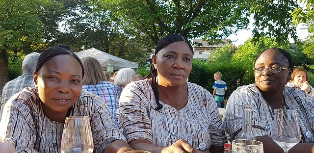 3 Frauen aus Nigeria sitzen nebeneinander mit je einem Getränk