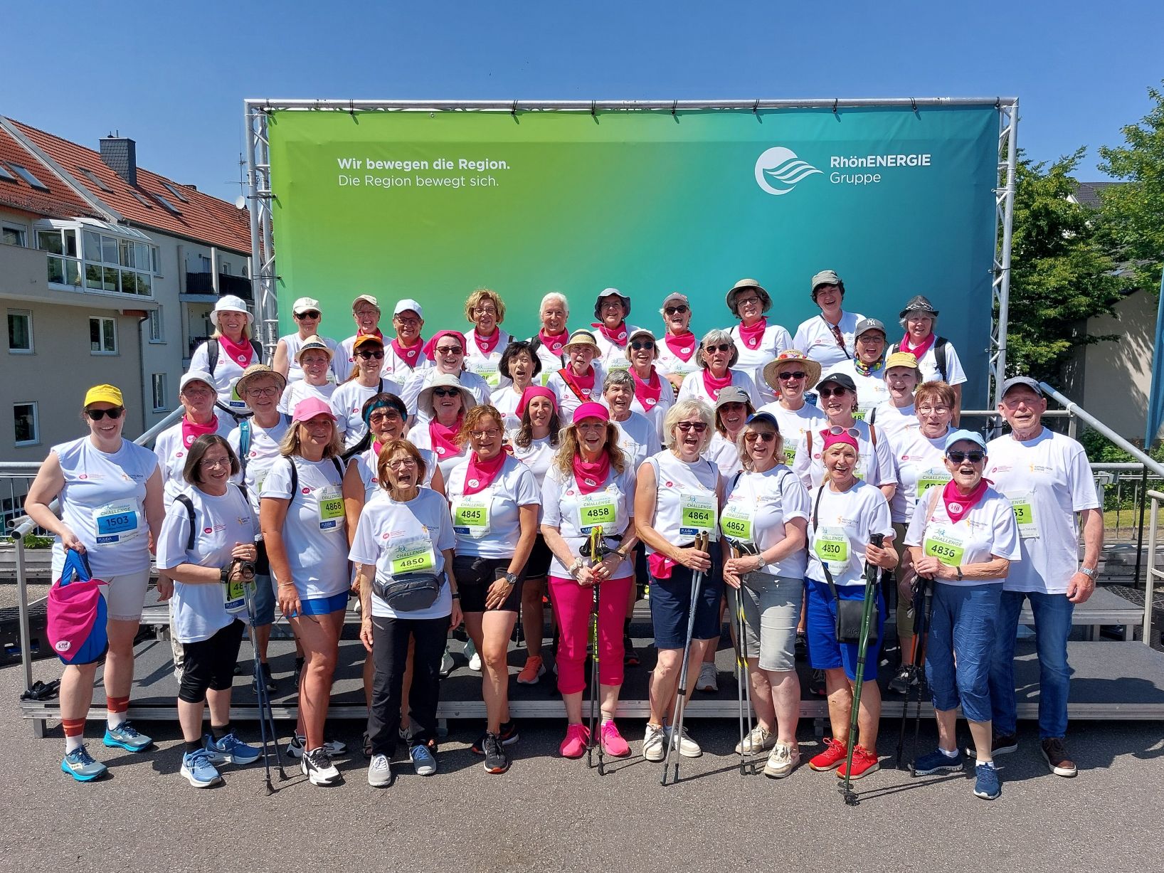 Gruppe von Frauen mit Laufstöcken und Startnummern auf den T-Shirts lachen in die Kamera
