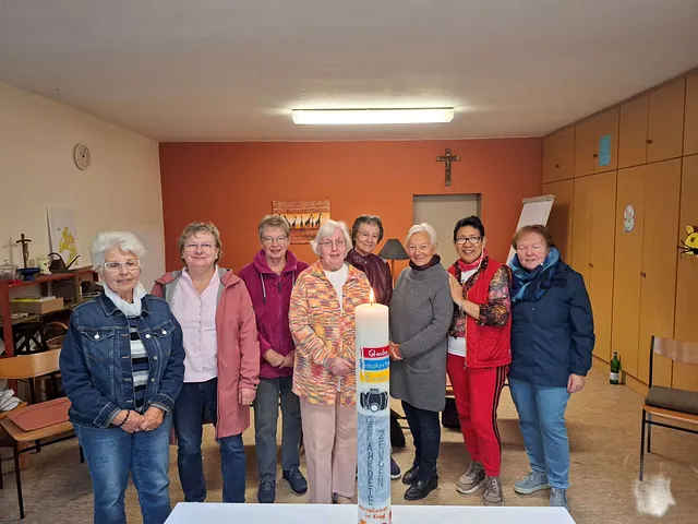 8 Frauen stehen hinter der entzündeten Wanderfriedenskerze