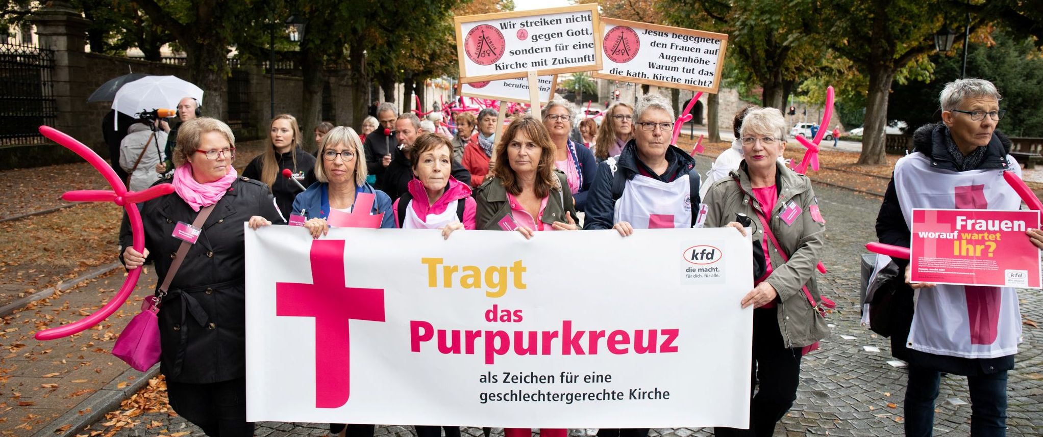 Viele Frauen Tragen ein Banner mit der Aufschrift "Tragt das Purpurkreuz", Lufballons und Plakate