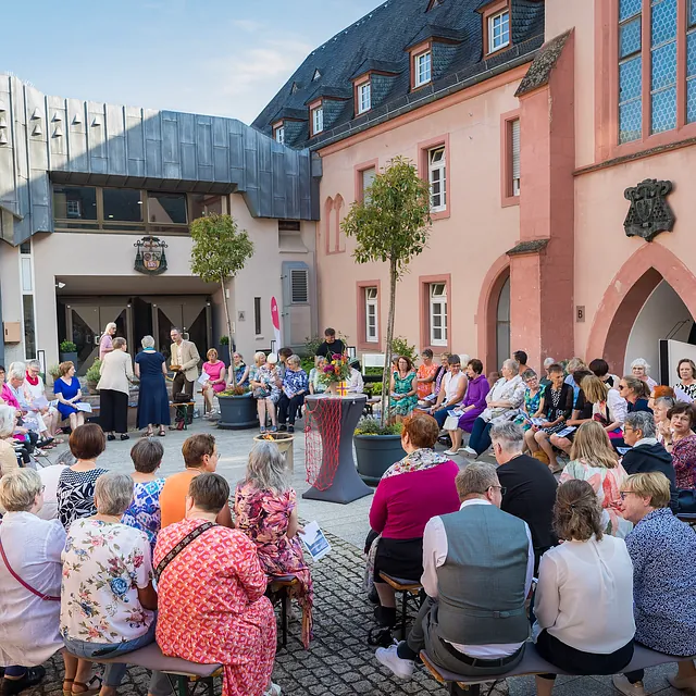 Viele Menschen sitzen um einen geschmückten Tisch und feiern Gottesdienst