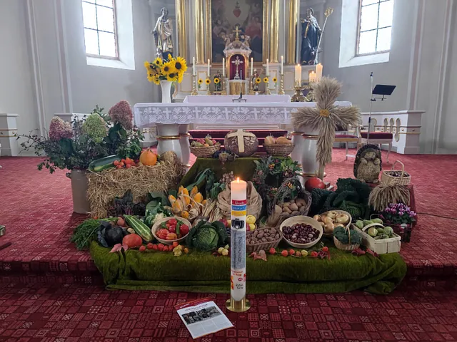 Vor dem Altar sind viele Früchte in Körben aufgebaut, davor steht die Wanderfriedenskerze
